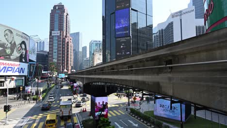 Iconic-and-busy-Bukit-Bintang-district-of-Kuala-Lumpur-with-the-monorail-train-entering-in-the-train-station,-Malaysia