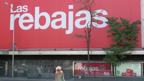 View-of-a-large-billboard-announcing-the-start-of-the-Summer-Sale-season-as-pedestrians-walk-past-it-in-Spain