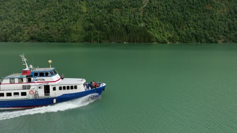 Front-of-a-tourist-sightseeing-boat-penetrating-through-glacial-turquoise-water-in-Fjaerlandsfjorden-Norway---60-fps-sideways-follow-aerial