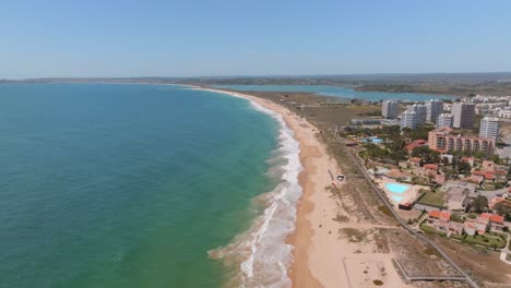 Drone-dolly-above-golden-sandy-beach-in-praia-dos-tres-Irmaos,-algarve-portugal