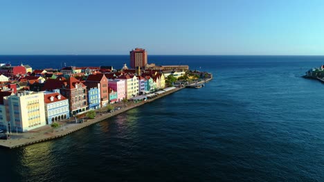 Vista-Panorámica-Aérea-De-Los-Alegres-Y-Luminosos-Edificios-De-Curazao-Al-Amanecer,-Mirando-Al-Océano