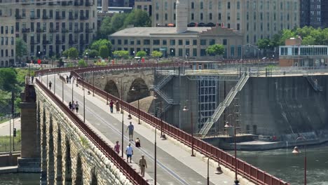 Pedestrians-walking-and-biking-on-the-Stone-Arch-Bridge-in-Minneapolis,-Minnesota