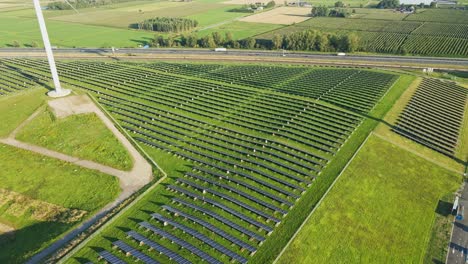 Drone-slowly-flying-over-next-to-photovoltaic-solar-panel-farm-next-to-a-busy-highway