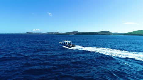 Rear-profile-side-tracking-follows-tourist-scuba-dive-tour-boat,-aerial,-caribbean-islands