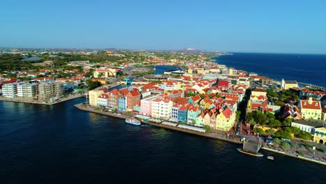 Willemstad-Curacao,-vibrant-brightly-colored-buildings-along-canal,-drone-wide-angle