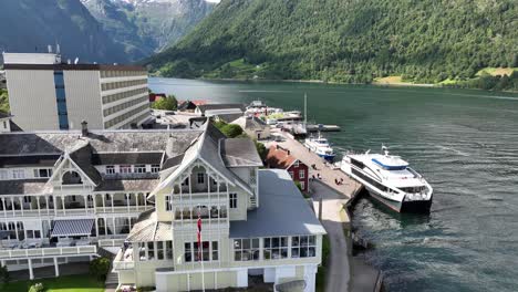 Balestrand-Noruega---Antena-Desde-El-Frente-Del-Hotel-Kviknes-Hasta-El-Concurrido-Muelle-Lleno-De-Turistas-Y-Barcos---Sognefjord-Y-Paisaje-De-Fondo-Durante-Las-Vacaciones-De-Verano