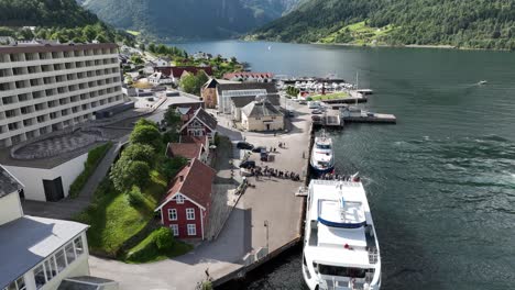 Long-line-of-passengers-waiting-to-board-passenger-boat-Vingtor-in-Balestrand-Norway---Summer-aerial
