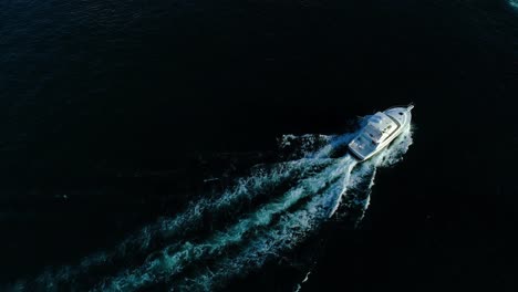 High-angle-drone-bird's-eye-view-follows-deep-sea-trolling-fishing-boat-in-open-ocean
