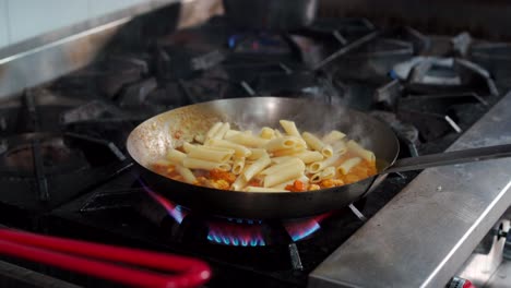Saute-pan-pasta-with-shrimps-penne-cannelloni-recipe-on-fire-stove-searing-over-fry-pan-at-italian-latin-restaurant-kitchen-by-chef