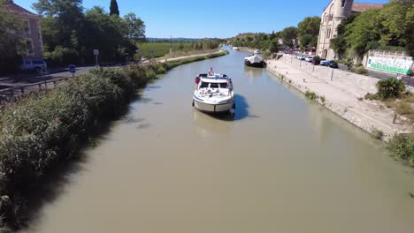 Canal-Du-Midi-En-Ventenac-En-Minervois-Mientras-Un-Barco-Pasa-Por-Debajo-De-Un-Puente-En-El-Pueblo-En-Un-Cálido-Día-De-Verano