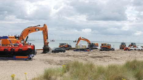 Coastal-construction-and-defences-meeting-on-the-beach-at-the-coast-with-workers-and-heavy-machinery-editorial