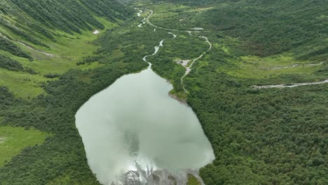 Green-lake-Brevatnet-in-Fjaerland-Norway---Aerial-moving-down-from-Boyabreen-glacier-glacier-towards-lush-green-lake-and-valley