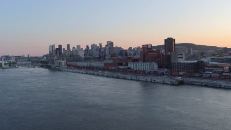 Aerial-View-From-Over-the-River-of-the-Downtown-Montreal-Waterfront-and-Skyline-at-Sunset
