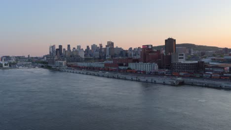 Luftaufnahme-Vom-Flussufer-Der-Innenstadt-Von-Montreal-Und-Der-Skyline-Bei-Sonnenuntergang