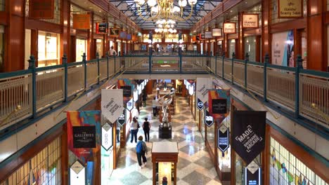 Static-shot-from-second-floor-capturing-the-interior-of-Brisbane-arcade-with-Mirage-sculpture-by-Gidon-Graetz-as-the-centrepiece,-shoppers-shopping-at-designer-boutiques-at-the-fashion-laneway