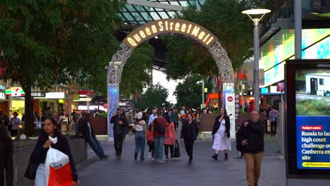 Static-shot-capturing-people-shopping-and-dinning-at-bustling-Queen-street-mall-at-night,-large-crowds-in-downtown-Brisbane-city-with-light-up-landmark-archway-sign-at-Albert-street
