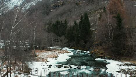 Antena-A-Lo-Largo-De-Un-Río-Congelado-Y-Cruzando-Un-Pequeño-Puente-En-Noruega