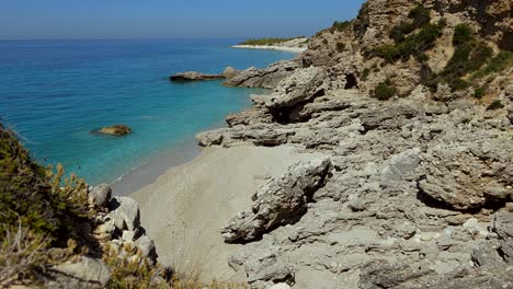 Secret-beach-isolated-by-cliffs,-white-sand-washed-by-turquoise-sea-water-on-summer-vacation-in-Mediterranean