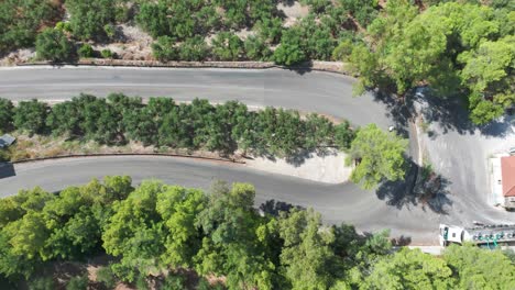 Static-Birdseye-Aerial-View-of-Traffic-on-Winding-Road-in-Green-Landscape-of-Greek-Island,-High-Angle-Drone-SHot