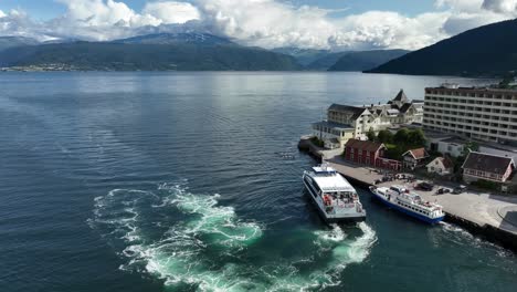 High-speed-catamaran-Vingtor-arriving-in-Balestrand-in-Sognefjord-Norway---Full-panoramic-aerial-orbit-showing-full-town-and-dock-view---60-fps