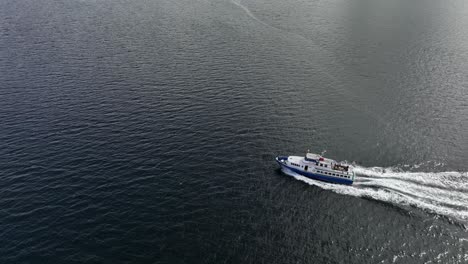 Umlaufende,-Hochwinkelige-Luftaufnahme-Eines-Charter-Touristenboots,-Das-Im-Sommer-Durch-Norwegische-Fjorde-Fährt,-Mit-Glücklichen-Touristen,-Die-Draußen-Auf-Dem-Achterdeck-Sitzen-–-60-Fps