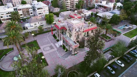 Aerial-orbit-over-the-Falabella-Palace-located-in-Providencia,-part-of-the-heritage-of-Santiago,-a-place-of-recreation-for-the-family