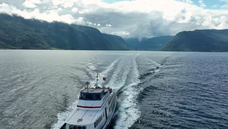 Vorderansicht-Des-Sognefjord-Touristenbootes,-Das-Die-Drohne-überholt-Und-Im-Unteren-Bild-Verschwindet-–-Vik-Sogn-Im-Hintergrund