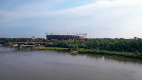 Aerial-view-of-PGE-Narodowy-Stadium-over-Vistula-River,-Warsaw,-Poland