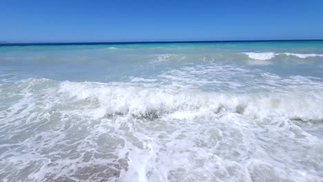 Panoramic-coastline-with-beautiful-colors-of-blue-turquoise-sea-water-and-white-waves-splashing-empty-beach-in-Mediterranean