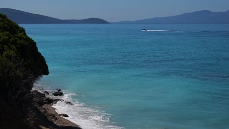 Beautiful-shoreline-in-Ionian-sea-with-turquoise-seawater-and-white-waves-splashing-on-hidden-beach