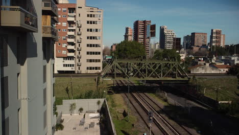 Roter-Zug-Fährt-über-Die-Brücke-In-Der-Stadt,-Sommer,-Buenos-Aires