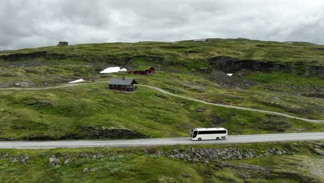 Weißer-Touristenbus,-Der-Im-Sommer-Am-Norwegischen-Gebirgspass-Vorbeifährt---Seitlich-Der-Luftaufnahme-Folgend