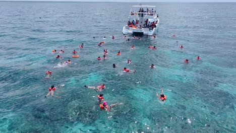 People-jumping-and-diving-from-touristic-boat-for-snorkeling-in-coral-reef