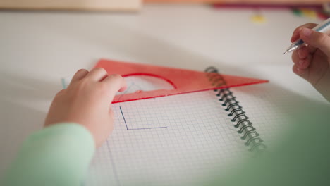 Little-student-draws-triangular-shape-with-ruler-and-pen