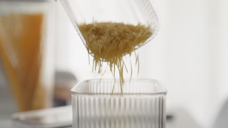Person-pours-short-spaghetti-into-container-measuring-portion