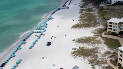 Video-Aéreo-De-Silver-Dunes-Condominiums-Beachfront-Resort,-Destin,-Florida,-Estados-Unidos-Y-Costa-Con-Coloridas-Sillas-De-Playa,-Sombrillas,-Nubes-Cielo-Azul,-Vista-Aérea-Del-Parque-Estatal-Henderson-Beach