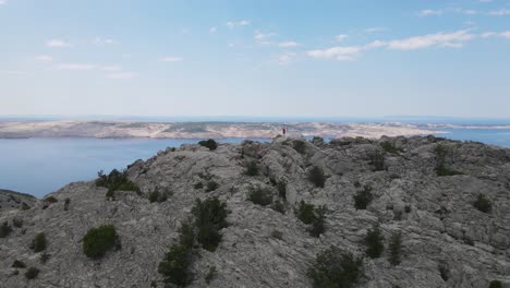 Vorwärts-Luftaufnahmen-Einer-Sonnenverbrannten-Steinigen-Insel-Pag-In-Kroatien-Mit-Dem-Berg-Velebit-In-Der-Ferne
