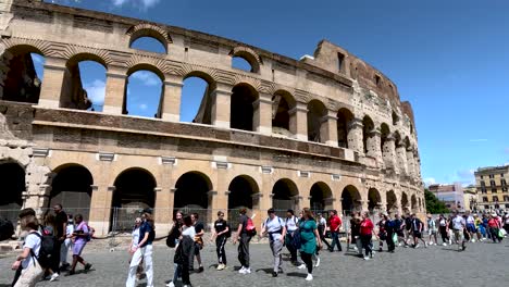 Crowds-Of-Young-Teenagers-Walking-Past-Exterior-Of-The-Colosseum-In-Rome-On-Clear-Sunny-Day