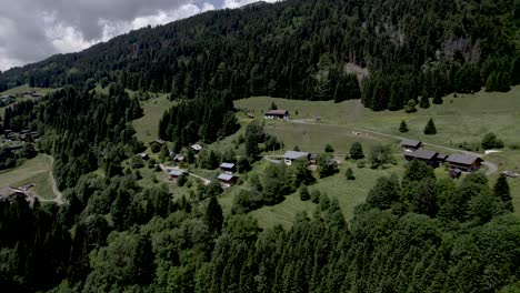 Aerial-approach-French-Alps-green-mountain-slope-above-village-Les-Gets-during-summer