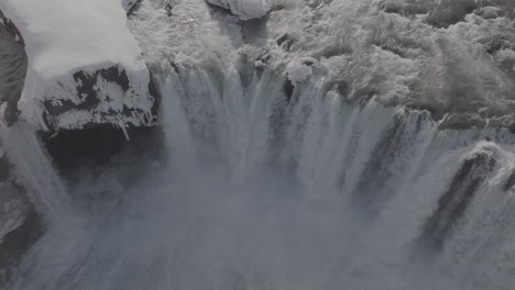 Luftaufnahme-Von-Kaltem-Gletscherwasser,-Das-An-Einem-Sonnigen-Wintertag-In-Island-In-Die-Schlucht-Fällt