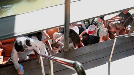 Un-Grupo-De-Turistas-Chinos-Preparándose-Para-Bajarse-De-Su-Barco-De-Madera-Alquilado,-Después-De-Su-Crucero-En-El-Mercado-Flotante-Damoen-Saduak,-Samut-Songkhram,-Tailandia