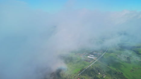 Looking-through-the-clouds-at-fertile-farmland-fields-below---aerial-view