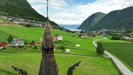 Top-of-Hopperstad-Stave-Church-Tower-in-Vik-Sogn-Norway---Aerial-orbit-with-parallax-and-fjord-view-in-background