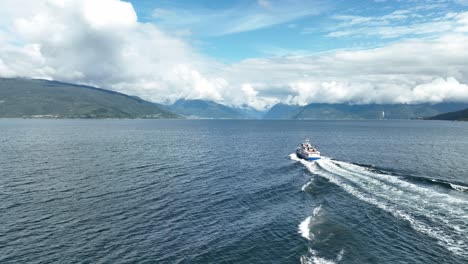 Luftaufnahme-Eines-Touristischen-Motorboots-Von-Hinten-Am-Sognefjord-In-Norwegen-Im-Sommer-–-Touristen-Sitzen-Auf-Dem-Achterdeck-Während-Einer-Urlaubsreise-Nach-Balestrand-Und-Fjærland-–-60-Fps