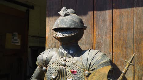Full-body-iron-armour-of-an-historic-knight-holding-an-axe-and-shield-in-front-of-wooden-door-of-the-warrior-for-empire-and-kingdom-based-in-England
