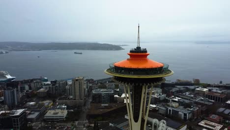 Fliegen-Um-Die-Seattle-Space-Needle-Mit-Düsterem-Elliot-Bay-Hintergrund---Luftaufnahme
