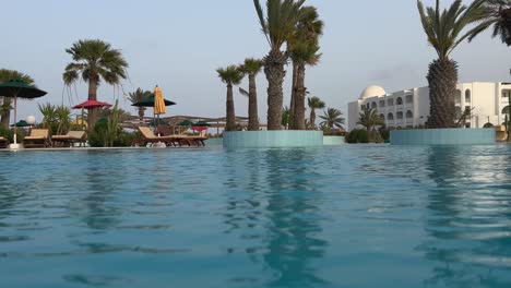 Low-angle-water-surface-view-of-swimming-pool-of-luxury-holiday-resort-in-Tunisia-at-sunset-on-windy-day