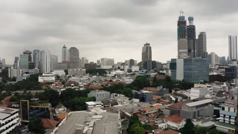 Aufsteigende-Drohnenaufnahme,-Die-Die-Innenstadt-Von-Jakarta-Mit-Hochhäusern-An-Einem-Grauen,-Bewölkten-Tag-Zeigt
