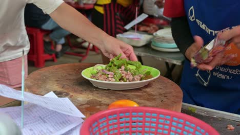 Vendedores-Ambulantes-Que-Sirven-Un-Plato-Lleno-De-Laab,-Una-Famosa-Comida-Callejera-Originaria-Del-Noreste-De-Tailandia,-En-La-Región-De-Isan