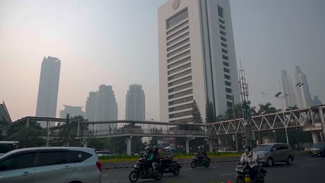 Skyline-buildings-and-busy-roads-at-office-hours-under-grey-and-hazy-sky-due-to-air-pollution-and-climate-change,-Indonesia